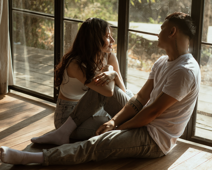 couple sitting on the floor looking outside the window, What Both Partners Are Actually Feeling Beneath the Surface, relationship attachment style