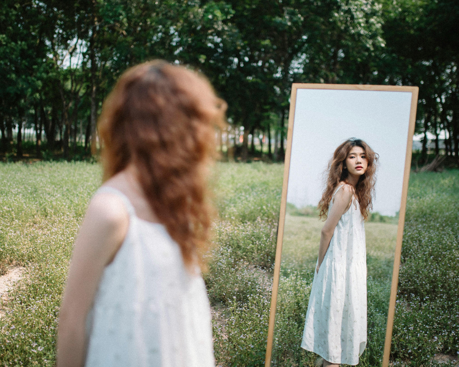 woman standing in front a mirror in nature looking at her self, mind shift and comparison